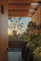 Une porte en bois donnant sur un balcon d’où l’on peut admirer un panorama sur la ville au coucher du soleil.
