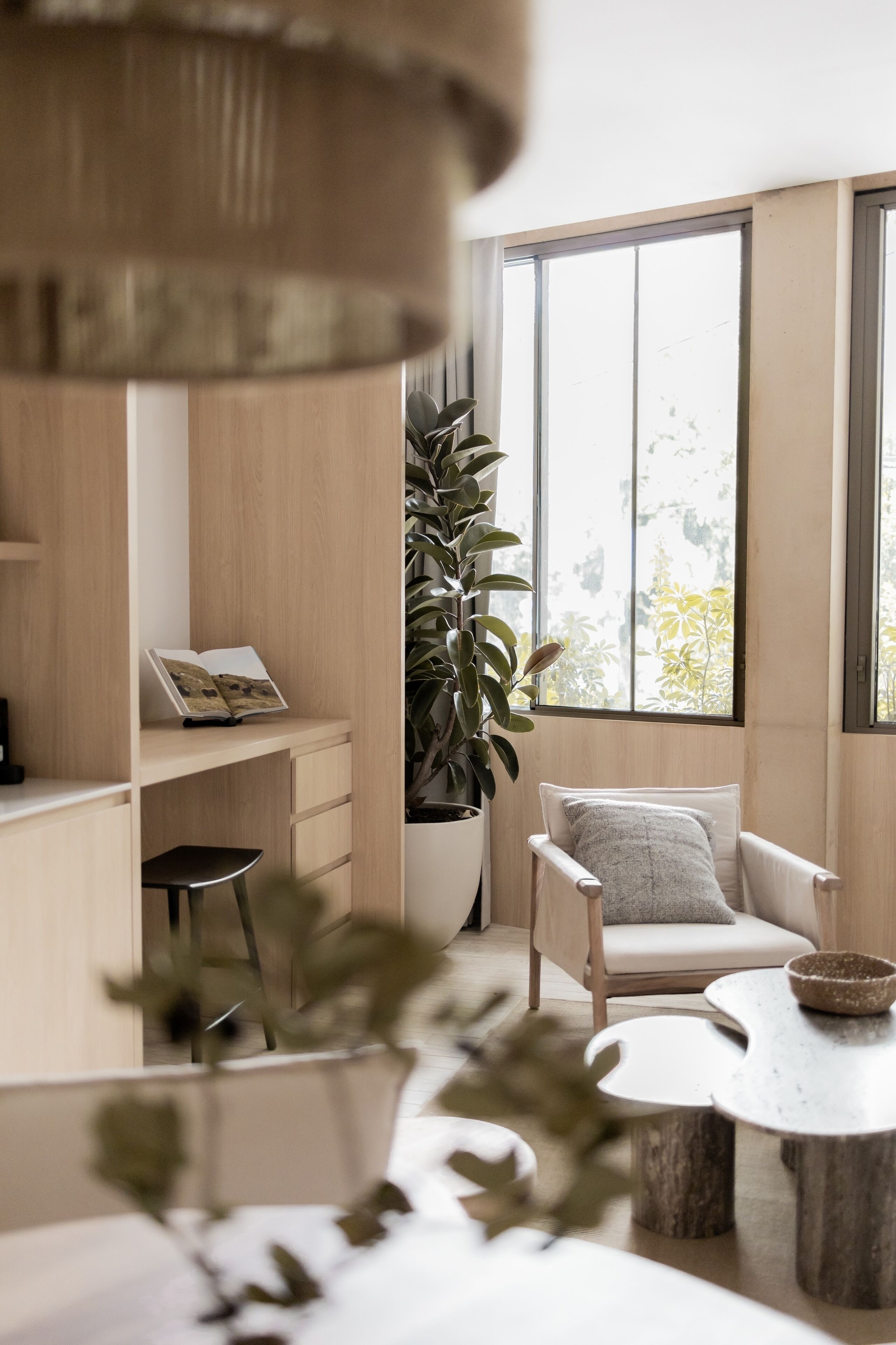 Un espacio habitable moderno con un ventanal grande, una planta en maceta, una silla blanca y una mesa redonda.