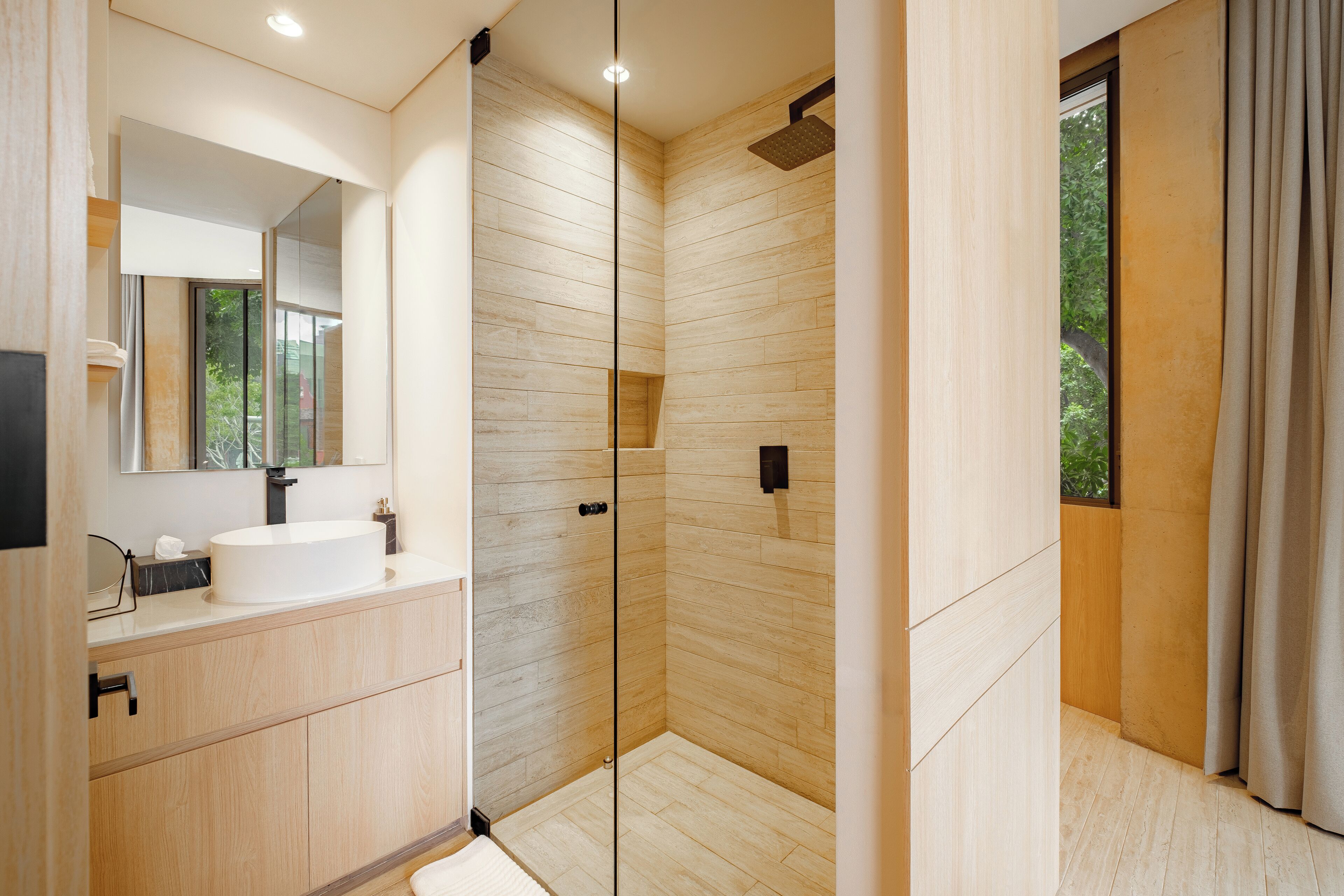 A modern bathroom with a glass shower enclosure, a sink with a mirror, and wooden cabinetry.