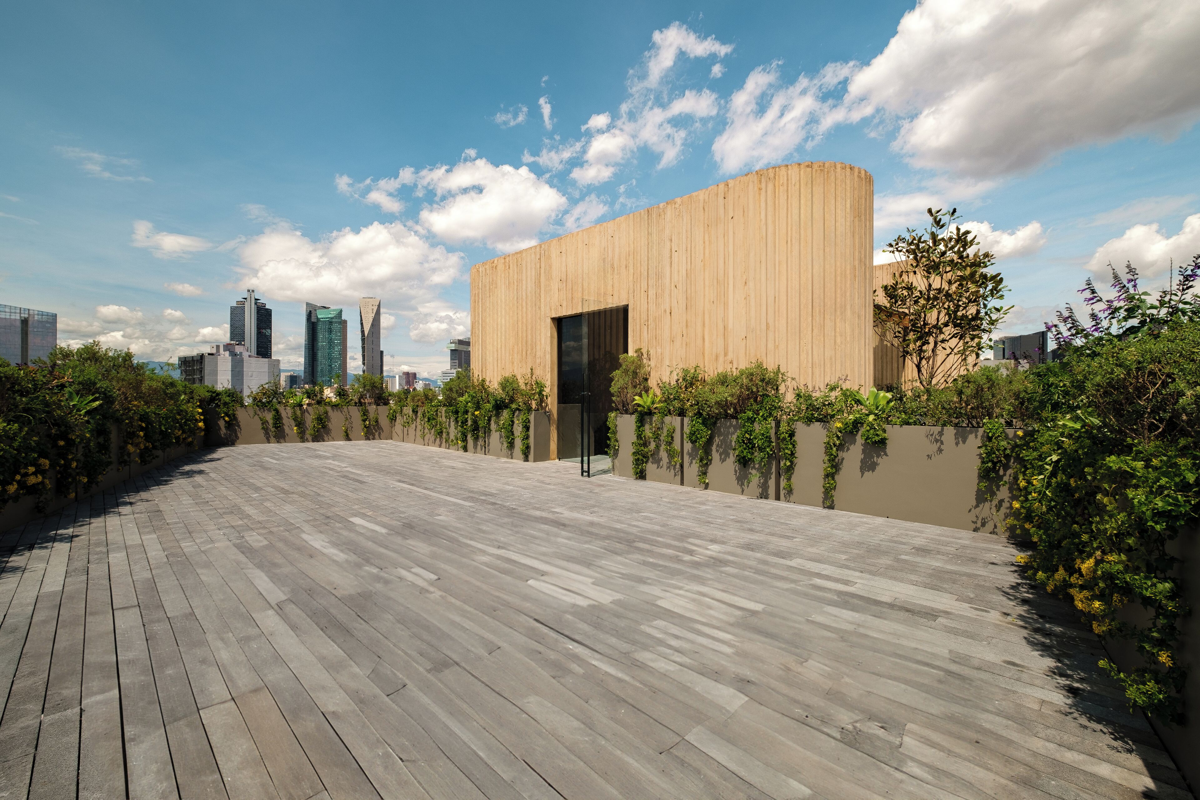 Ein modernes Gebäude mit Holzfassade und flachem Dach, umgeben von Grünflächen und einem gepflasterten Weg.