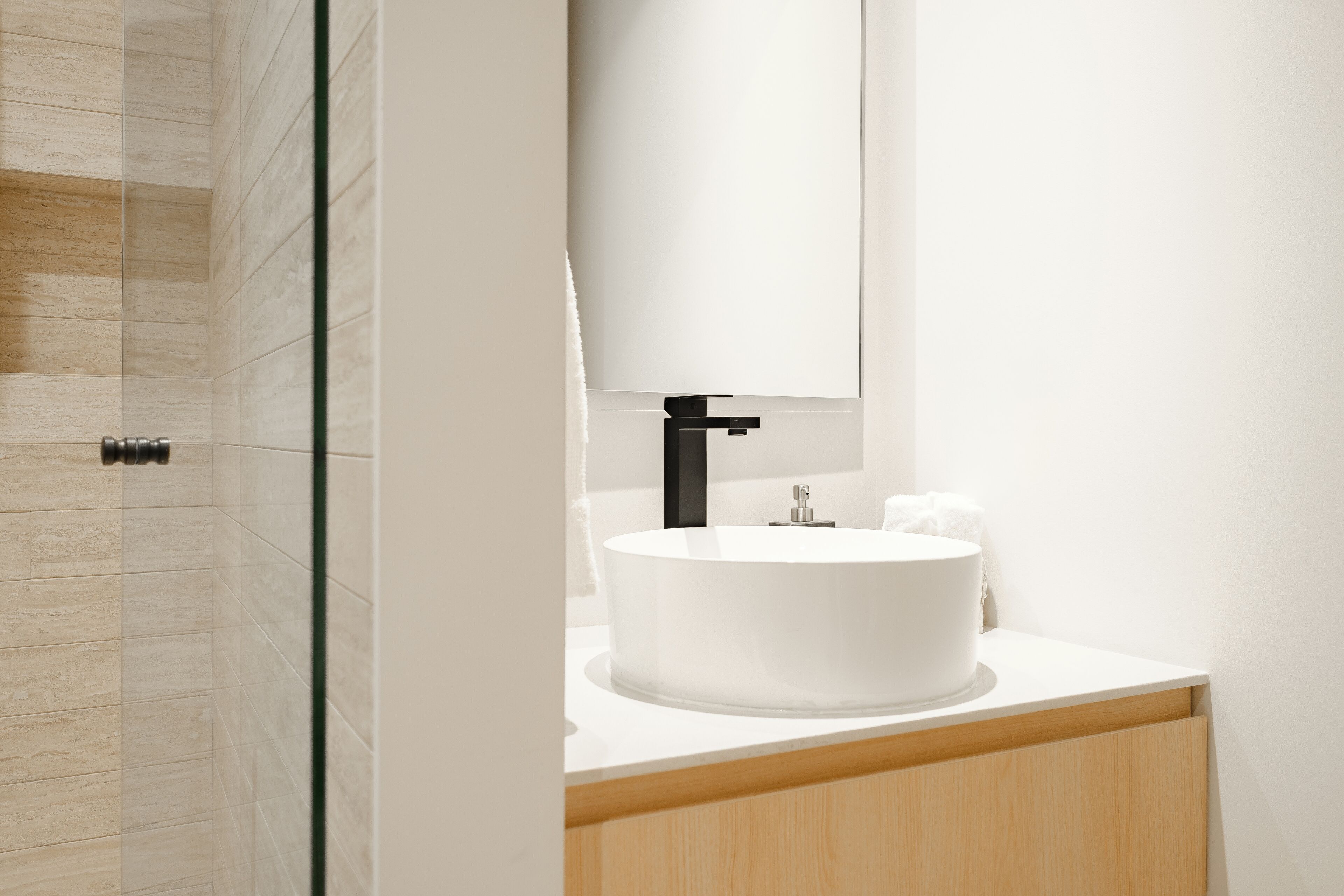 A modern bathroom with a white sink, black faucet, and a mirror above it.