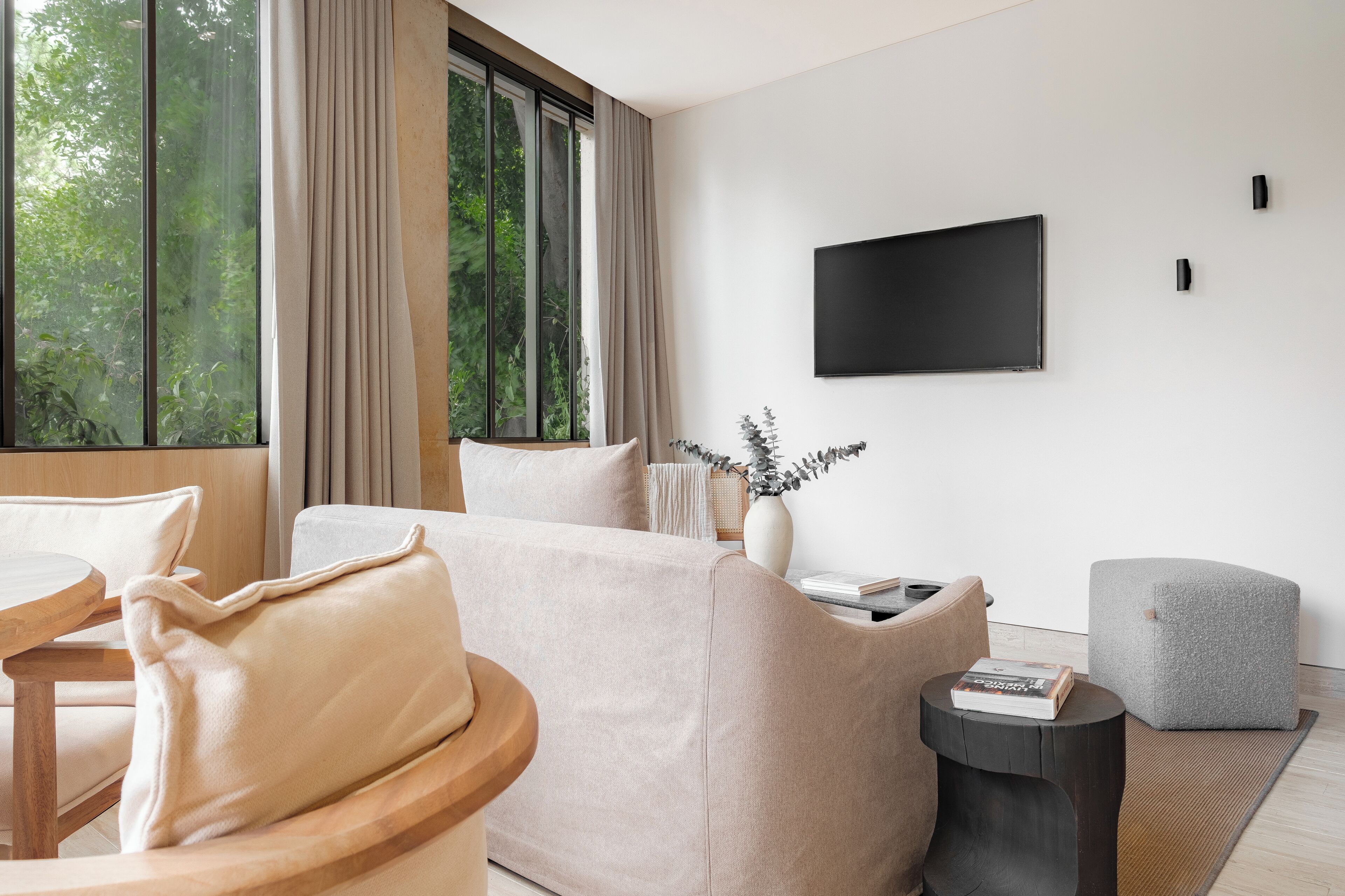 A modern living room with a large window, a flat-screen TV, and a cozy seating area.