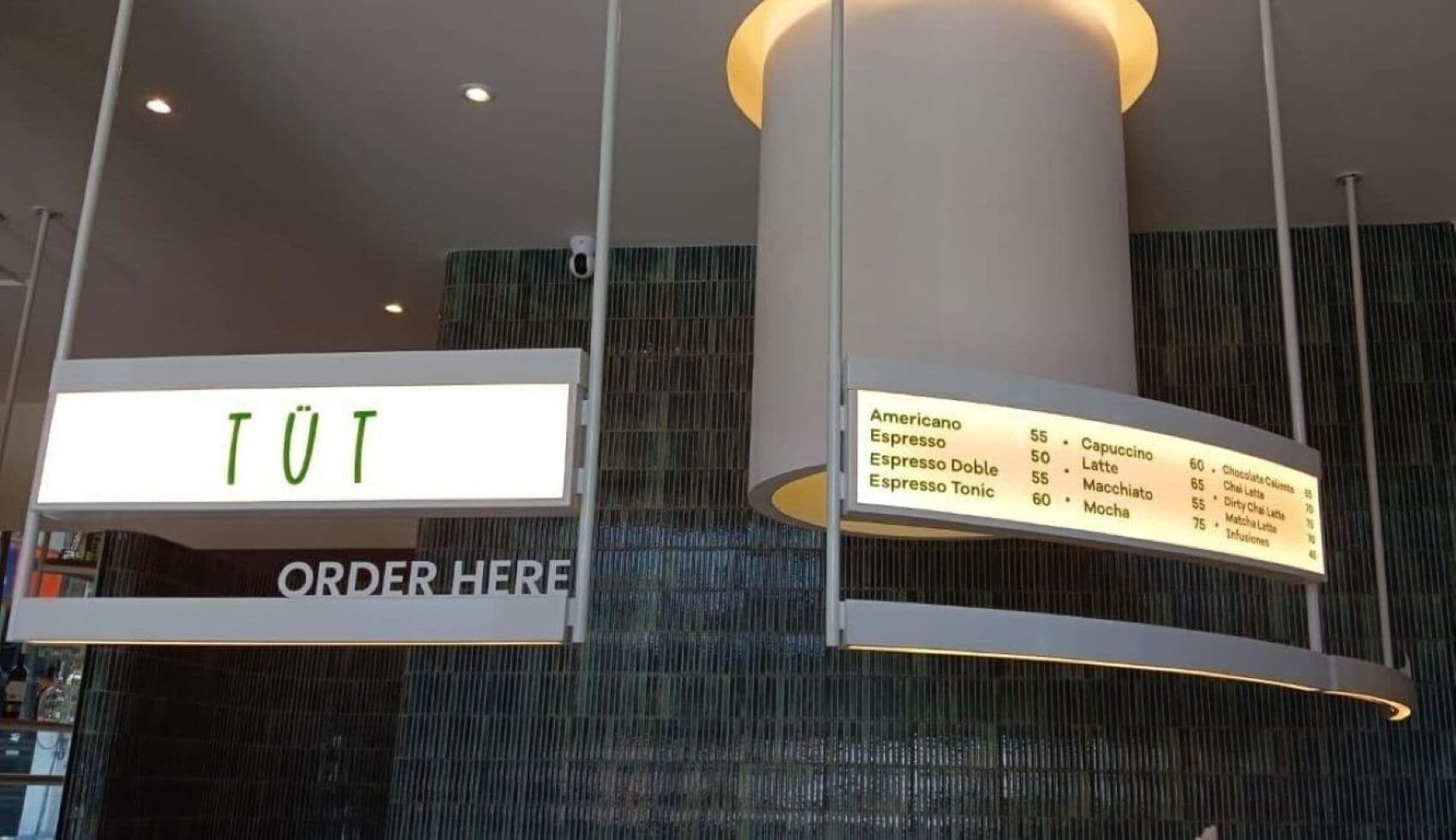 A menu board with various coffee and tea options and prices, and a sign above it that says 'ORDER HERE'.