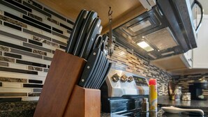 Une cuisine équipée d’un bloc à couteaux, d’une cuisinière et d’un étagère à épices.