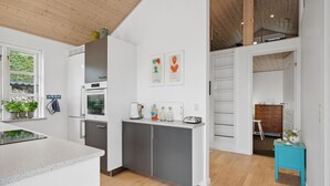A modern kitchen with white cabinetry, a built-in oven, and a countertop with various appliances and decorations.