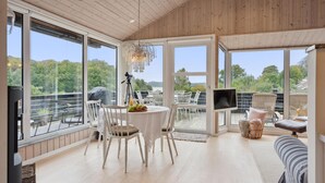 A spacious indoor area with large windows, a round table with chairs, and a television.