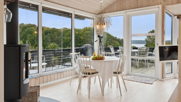 A dining area with a table, chairs, and a view of a lake.