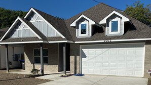 Een woonhuis met een garage, een overdekte oprit en een verzorgd gazon.