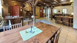 Un comedor rústico con mesas y sillas de madera, un piano y una chimenea de piedra.