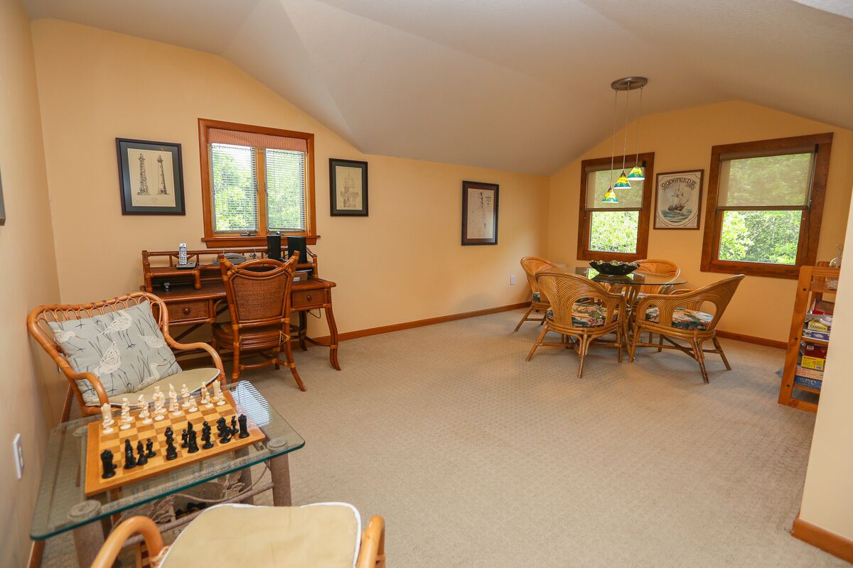 A cozy living room with a chessboard, wicker furniture, and framed artwork on the walls.