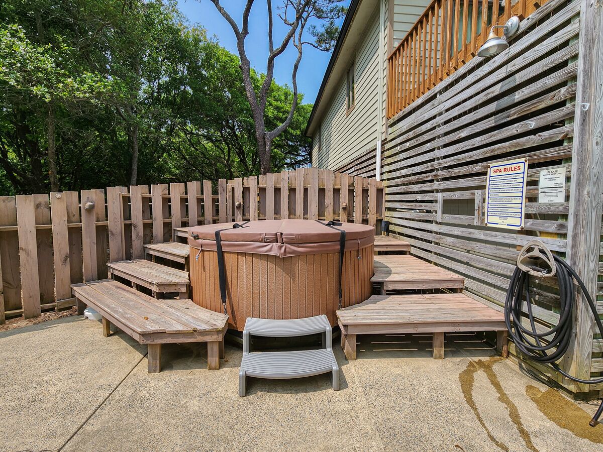 A hot tub area with wooden benches and a step stool, surrounded by a wooden fence.