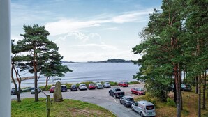 A parking lot with cars and a van, surrounded by trees and a body of water in the background.