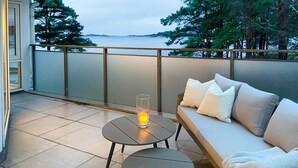 A balcony with a sofa, two small tables, and a candle.