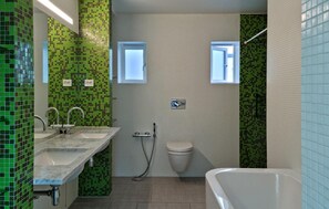 Une salle de bain avec des carreaux de mosaïque verts, un lavabo blanc, des toilettes et une baignoire.