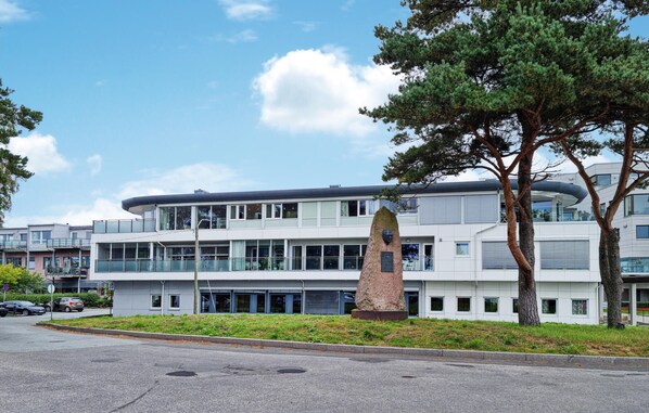 Un bâtiment moderne doté d’un toit plat, de grandes fenêtres et d’une sculpture centrale.