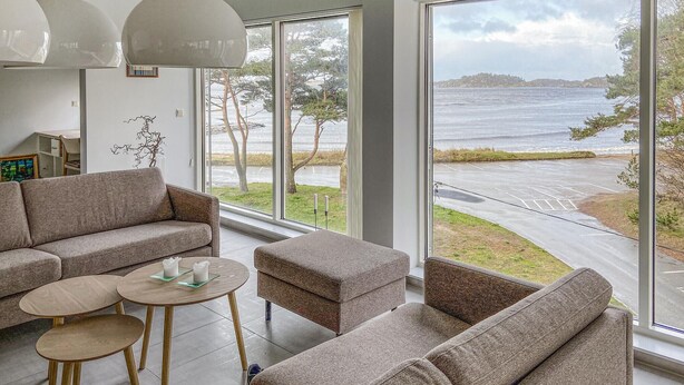 A modern living room with a large window overlooking a body of water and a road.