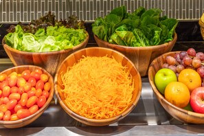 Ein Buffet mit verschiedenen Speisen, darunter Salate, geriebenem Käse, Trauben und Früchten.