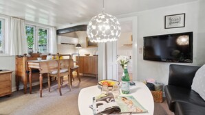 A modern living room with a dining area, a kitchen, and a TV mounted on the wall. - 3 bedroom gorgeous home in Nexø (Nexø)
