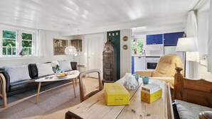 A living room with a sofa, a coffee table, and a dining area with a table and chairs. There is a kitchen visible in the background. - 3 bedroom gorgeous home in Nexø (Nexø)