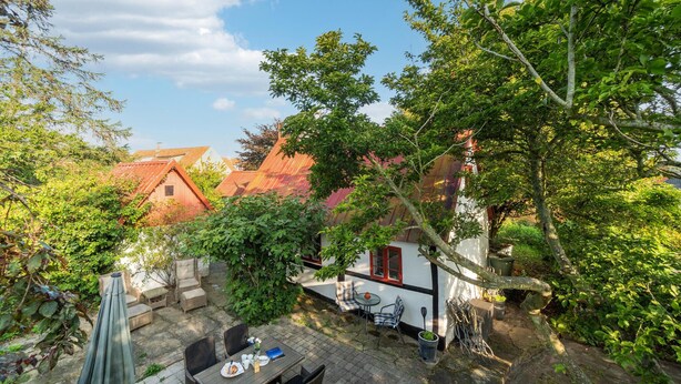 A courtyard with a dining area, outdoor furniture, and a small white building with red accents. - 3 bedroom gorgeous home in Nexø (Nexø)