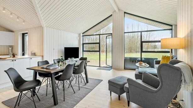 Un amplio espacio de estar con una mesa de comedor, sillas y un sofá. Una ventana grande ofrece vistas al exterior.