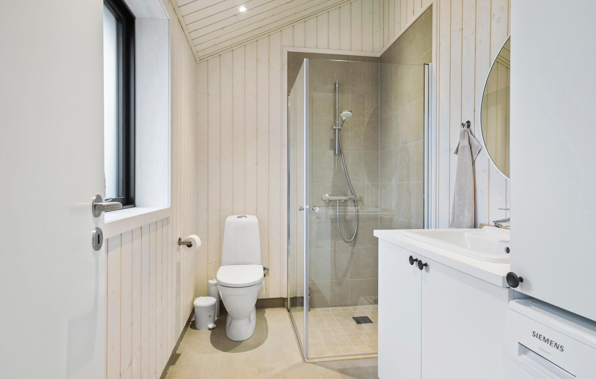 A modern bathroom with a toilet, shower, and sink.