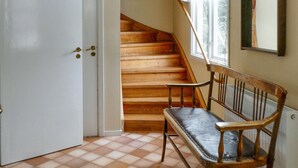 A wooden staircase leading to a landing, a bench, and a white door.