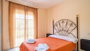Una habitación de hotel con cama, cortinas, un radiador y televisor.