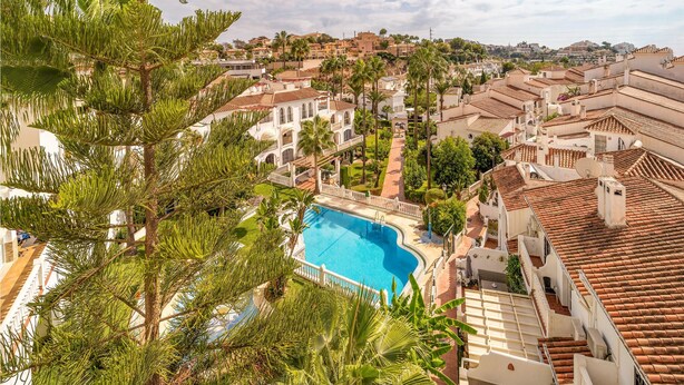Un resort con piscina rodeado de exuberante vegetación y arquitectura tradicional.