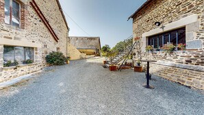 A cobblestone alley with stone buildings, a staircase, and outdoor seating.