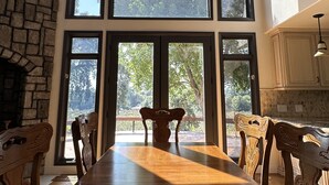 A dining area with a long wooden table, six chairs, and a stone wall.