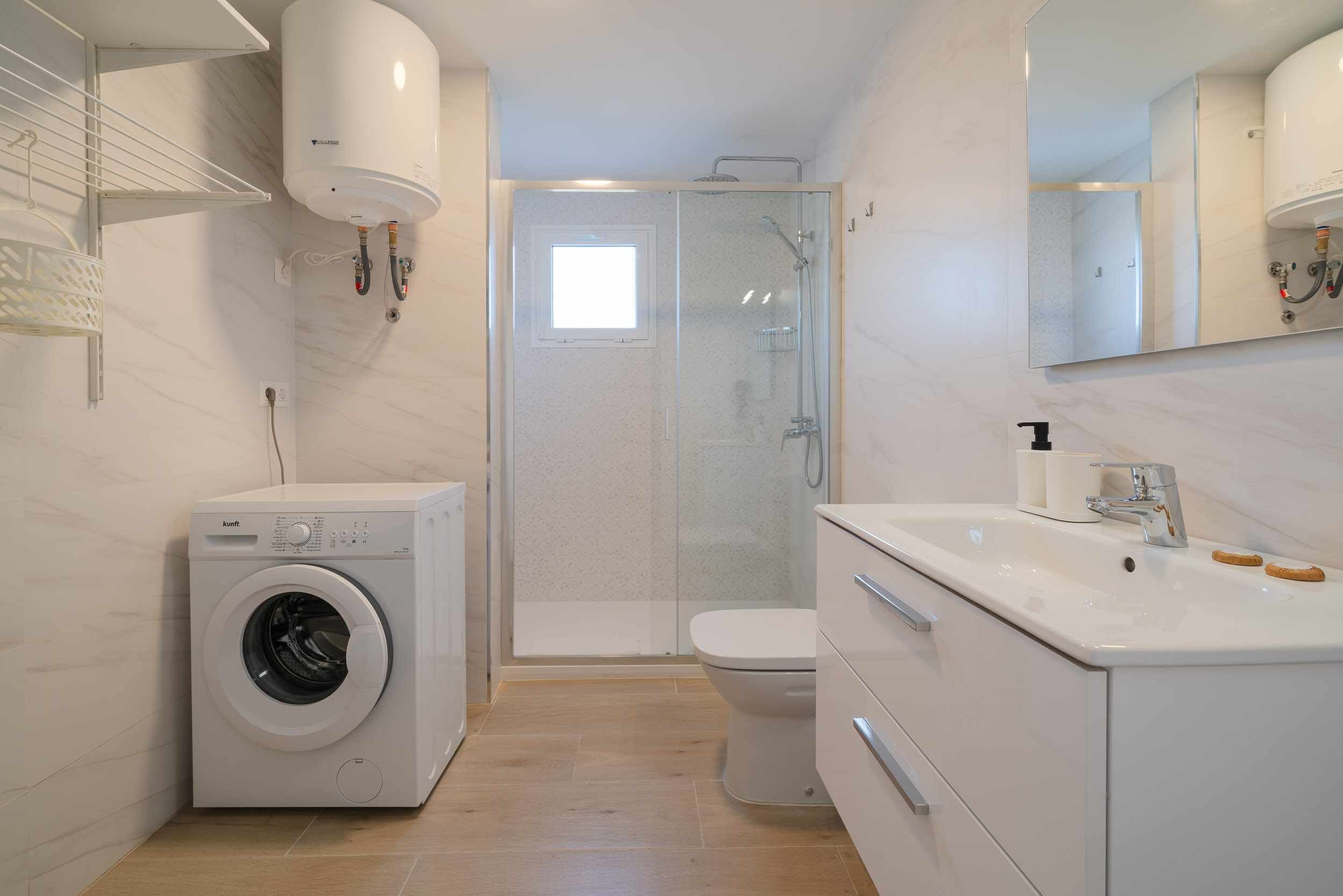 Ein modernes Badezimmer mit Waschmaschine, Toilette und Dusche.