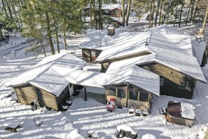 A snow-covered cabin with a sloped roof, a small attached shed, and a covered porch area with outdoor seating. - Cozy Vacation Retreat at Lake Harmony (Lake Harmony)