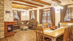 A cozy living room with a fireplace, wooden furniture, and a dining area with a table set for six.