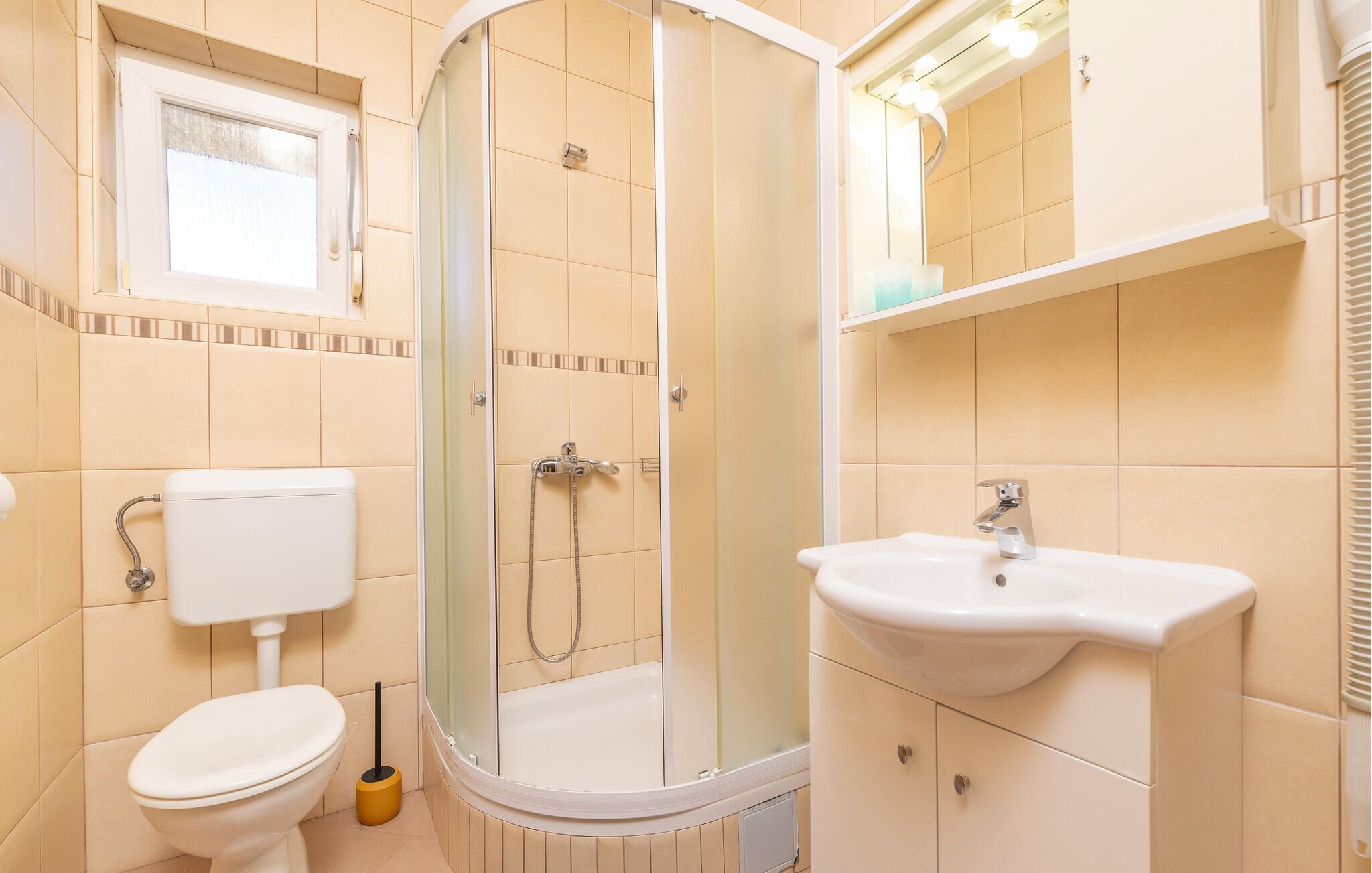 A bathroom with a toilet, a shower with a glass door, a sink, and a mirror.