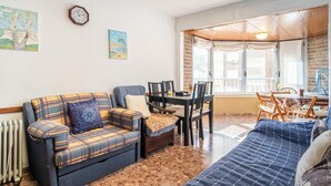 Una sala de estar acogedora con sofá, mesa de comedor con sillas y un ventanal con vistas a edificios.
