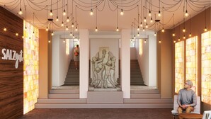 A modern interior with a central staircase, a stone sculpture, and a sign reading "SALZGUT".