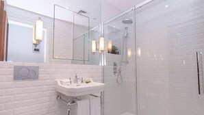 A modern bathroom with a glass-enclosed shower, a white sink, and a large mirror. - Modern, Luxurious 1BR Flat- Heart of Covent Garden (London)