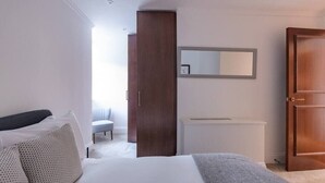 A bedroom with a bed, a wardrobe, a radiator, and a mirror on the wall. - Modern, Luxurious 1BR Flat- Heart of Covent Garden (London)