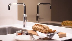A kitchen counter with a loaf of bread, a plate, and jars of condiments. - Modern, Luxurious 1BR Flat- Heart of Covent Garden (London)