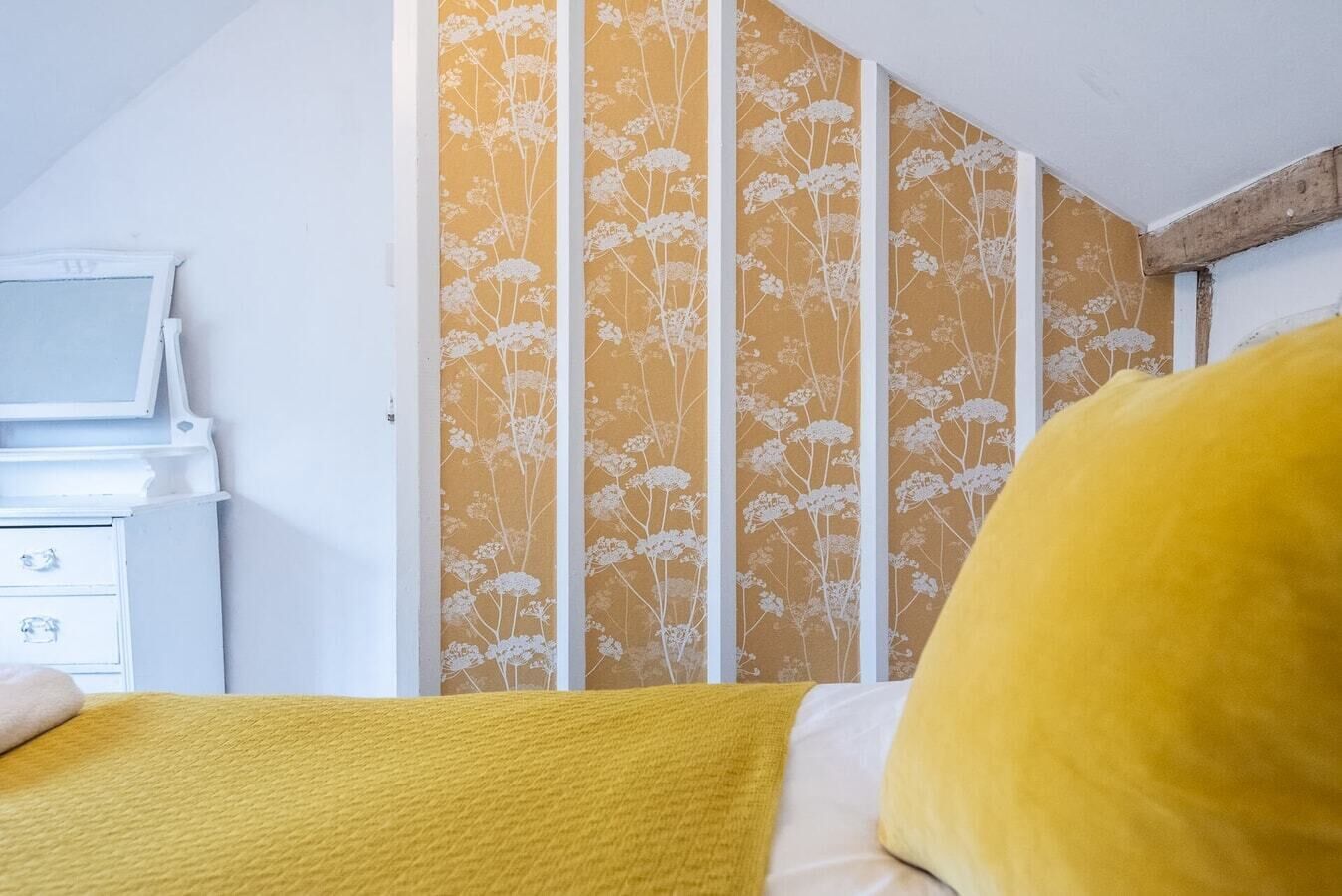 Ett sovrum med en säng, en vit byrå och en tv-apparat placerad på ett vitt skåp.
