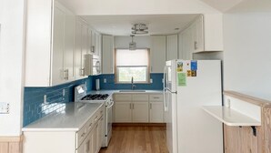 A compact kitchen with white cabinets, a gas stove, a sink, and a refrigerator. - 7692- Seaside Serenity - Pet-Friendly Avon Retreat | Sunsets & Sun Decks (Avon)