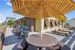 Relax on the spacious deck with Adirondack chairs, a dining table, and a shaded area under a large umbrella.