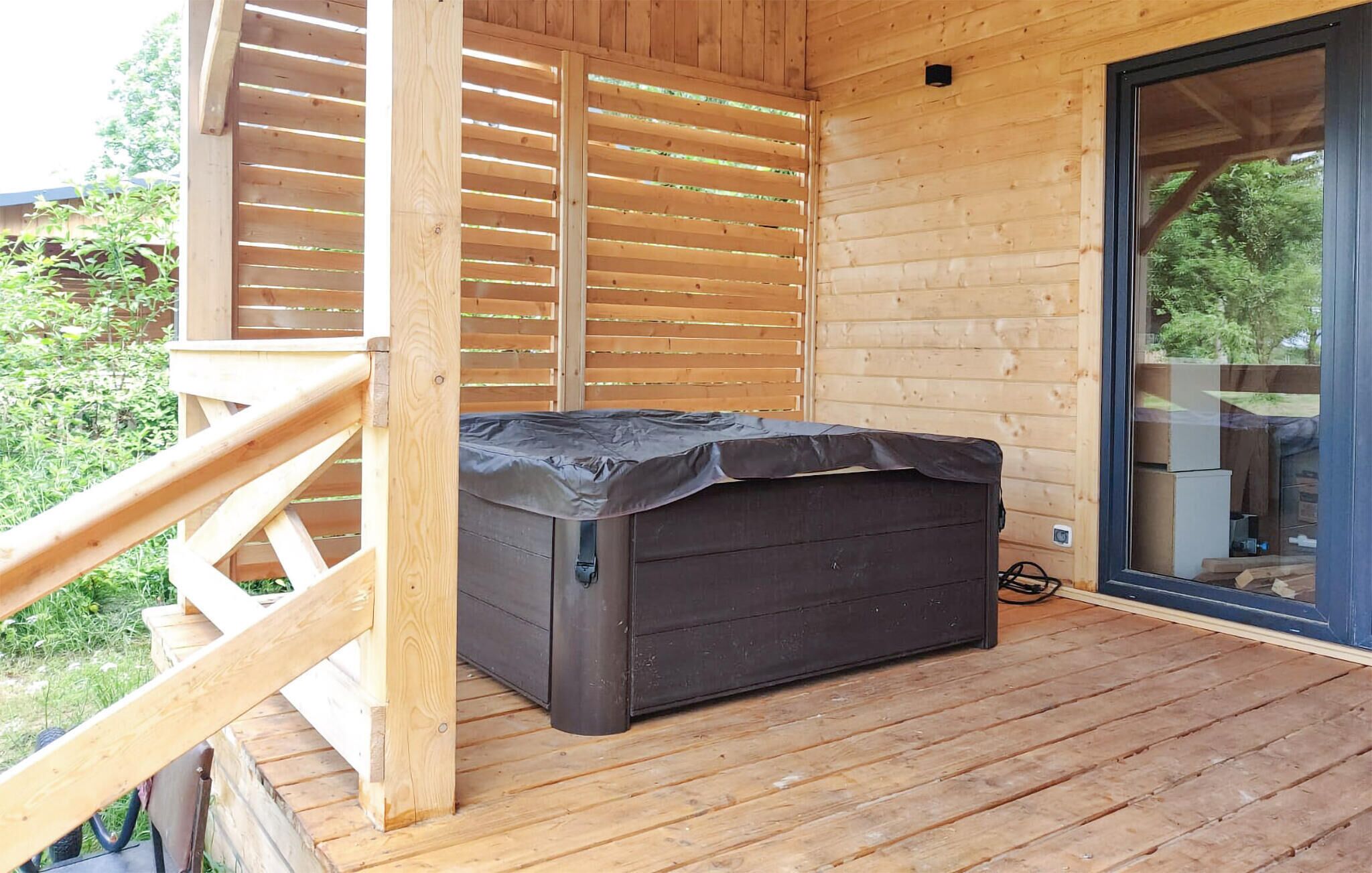 Une terrasse en bois dotée d’un espace salon extérieur couvert et d’une porte-fenêtre coulissante donnant sur un espace extérieur.