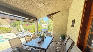 An outdoor patio with a table and chairs, a grill, and a pool. - Perfectly located amazing private single story home. (Las Vegas)