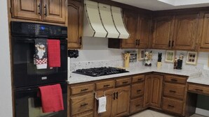 A kitchen with wooden cabinets, a black oven, a gas stove, and a marble countertop. - Perfectly located amazing private single story home. (Las Vegas)
