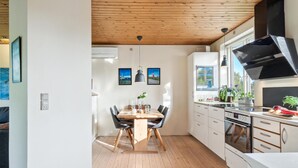 Uma cozinha moderna com piso de madeira, uma mesa de jantar com cadeiras e um fogão grande.