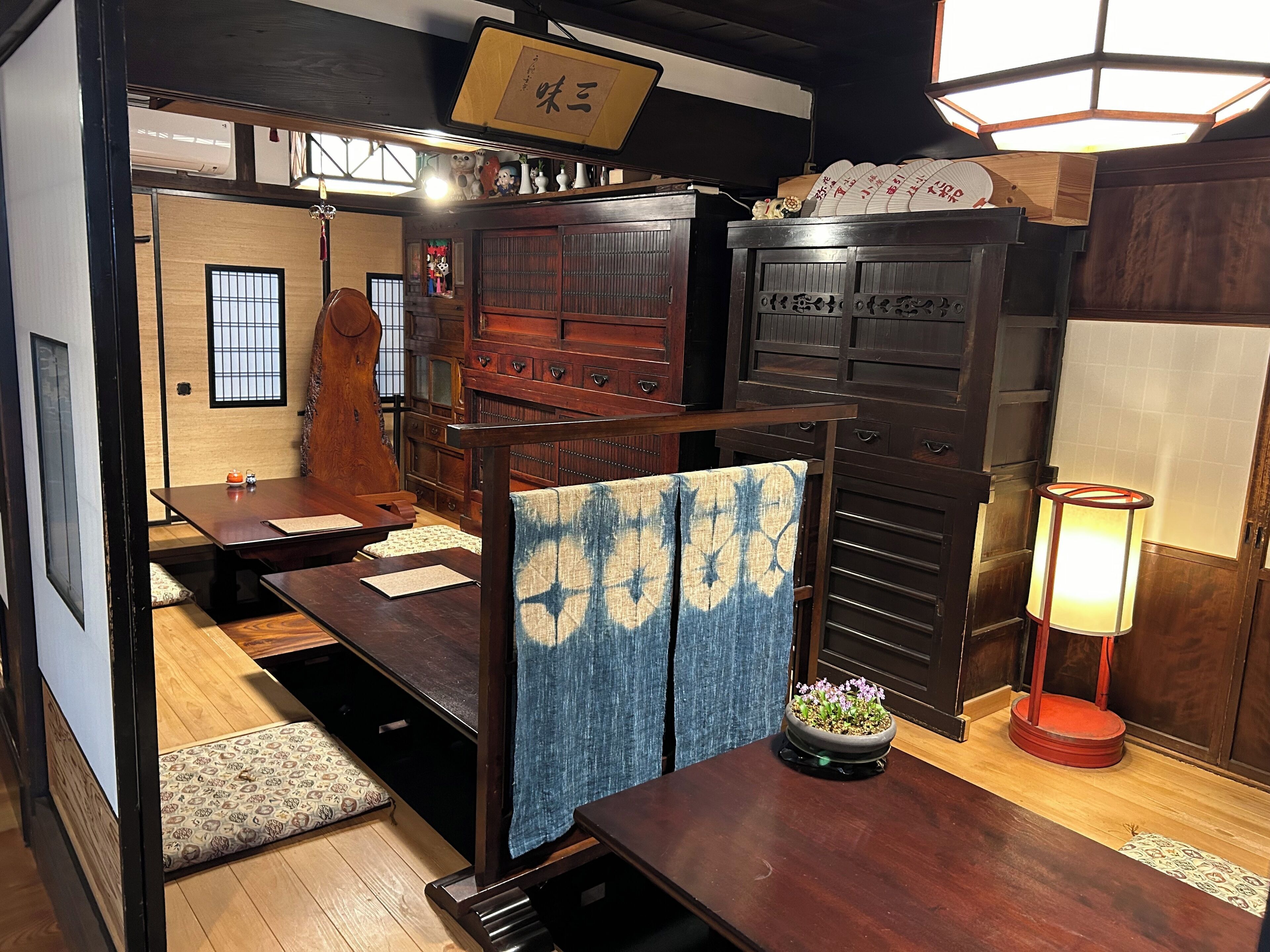 Une pièce de style japonais traditionnel, avec un sol recouvert de tatamis, une basse table en bois, un banc rembourré et une porte coulissante en papier de riz (shoji).