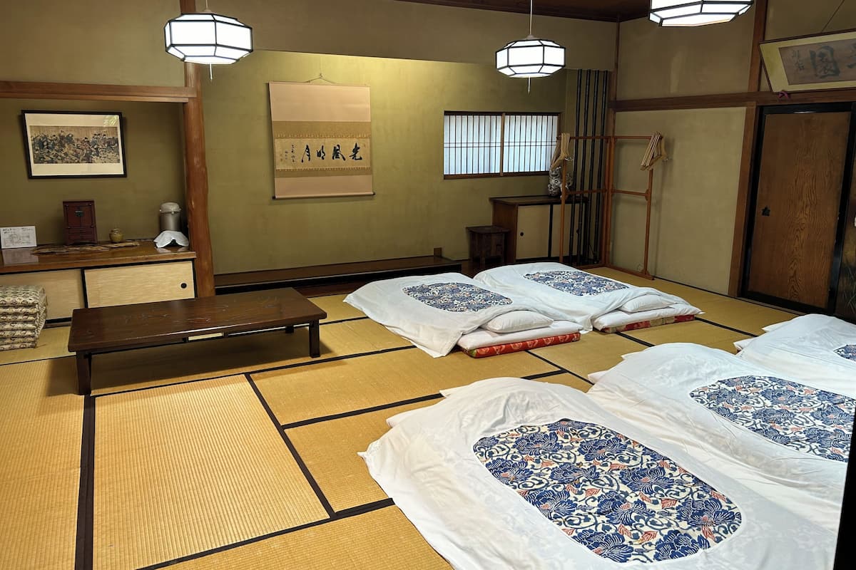 A traditional Japanese room with tatami flooring, low wooden tables, and hanging paper lanterns.