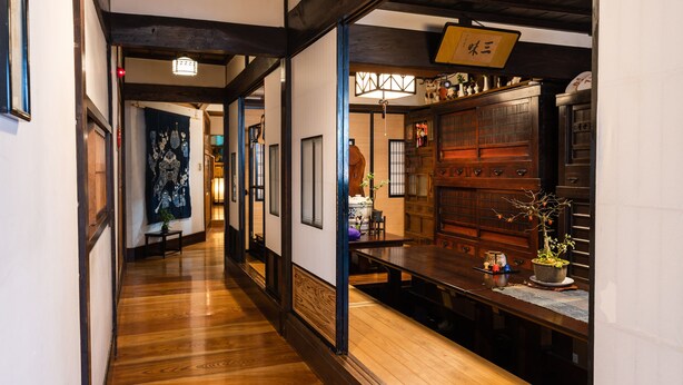 A traditional Japanese interior with wooden floors, tatami mats, and a reception desk. - Kappo Ryokan Uoichi (Shimada)